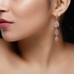Long earring with violet precious stones hang from woman’s ear
